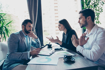 Three business partners in smart wear are discussing the finances of their company in a meeting in...
