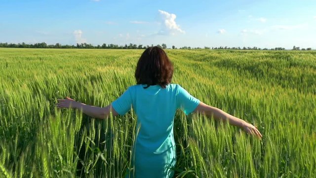 girl runs on a wheat field over a cloudy sky