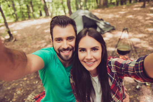 Selfie time! For a memories of vacation together. Cute lovers are making photo in a campsite, hugging, smiling, so happy