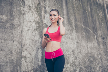 Summer, wellbeing, wellness, music and work out! Low angle portrait of sporty young lady in fashionable sport wear is listening to music and smiling, will start her training now