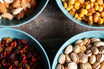 Mix of different type of nuts in bowls on wooden background