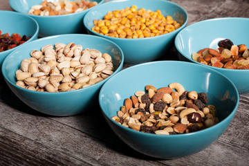Mix of different type of nuts in blue bowls on wooden background