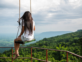 Lonely woman sit on handmade swing on the tree at top of mountain with landscape background, lonely and looking for something