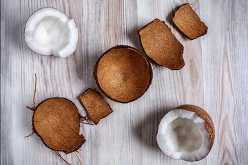 On the light surface of the table is two half the coconut in the hairy shell close up. Next to the...