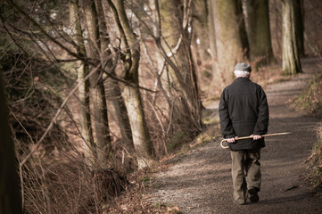 Elderly man going away in park. Toned