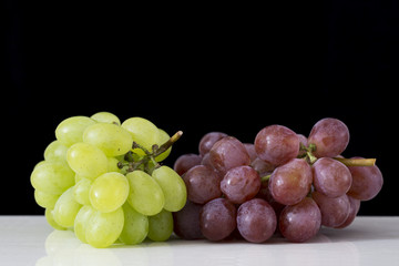 Fresh grapes on a white table and black background.