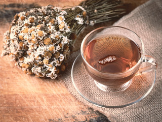 Cup of medicinal chamomile tea on a wooden