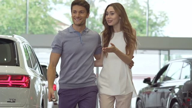Pretty young casual couple choosing car in dealership 
