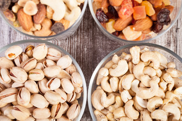 Healthy mix of dried nuts and sweets in was glass on wooden background in studio photo