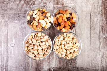 Healthy mix of dried nuts and sweets in was glass on wooden background in studio photo