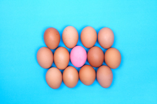 one preserved egg on blue background with chicken egg around.