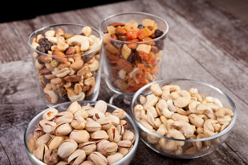 Healthy mix of dried nuts and sweets in was glass on wooden background in studio photo