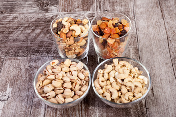 Fototapeta na wymiar Healthy mix of dried nuts and sweets in was glass on wooden background in studio photo