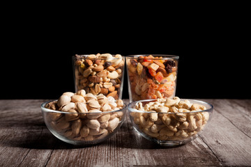 Healthy mix of dried nuts and sweets in was glass on wooden background in studio photo