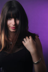 Fototapeta premium Portrait d' une belle femme brune tenant ses cheveux devant un fond violet 