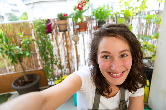 Young woman taking selfie on her city garden balcony - Technology and nature theme