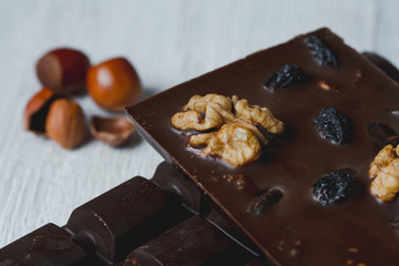 chocolate bar filled with different berries and nuts close-up  lie old wooden table with cracked paint