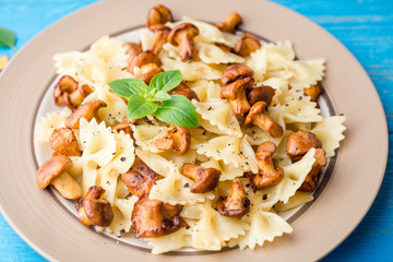 Farfalle pasta with chanterelles and basil on blue wooden table