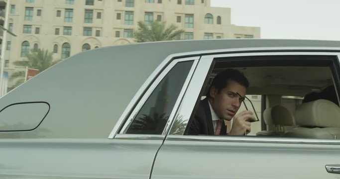 Businessman rides in limo, slow motion