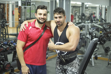 Obraz premium Brothers training in gym lifting weights, posing after training