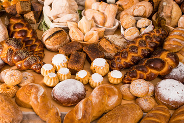 various types of fresh bread in a table: rum baba, challah, wheat and rye breads