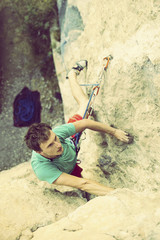 Obraz na płótnie Canvas Rock climber ascending a challenging cliff. Extreme sport climbing. Freedom, risk, challenge, success.