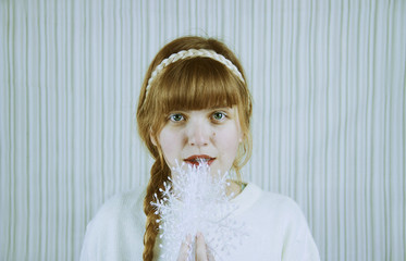 Retrato de una chica rubia sosteniendo un copo de nieve en navidad 