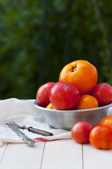 Red and yellow tomatoes in an old aluminum bowl on a wooden board outdoors. Tomatoes background.