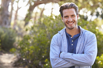 Portrait of young white man smiling arms crossed outdoors
