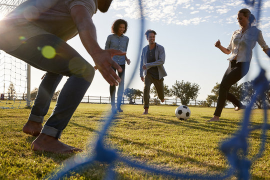 Young Woman Kicks Football While Playing With Friends