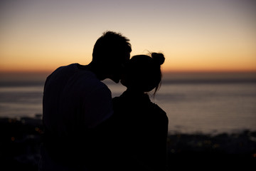 Couple kissing by the sea at sunset, silhouette