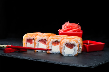 Traditional Japanese cuisine. Selective focus on sweet sushi rolls with salmon, cream cheese, rice and raspberry on dark background