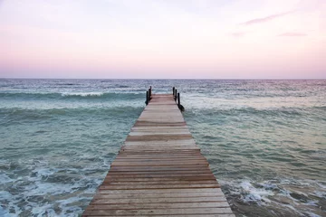 Foto op Plexiglas houten pier bij zonsondergang © comradelukich