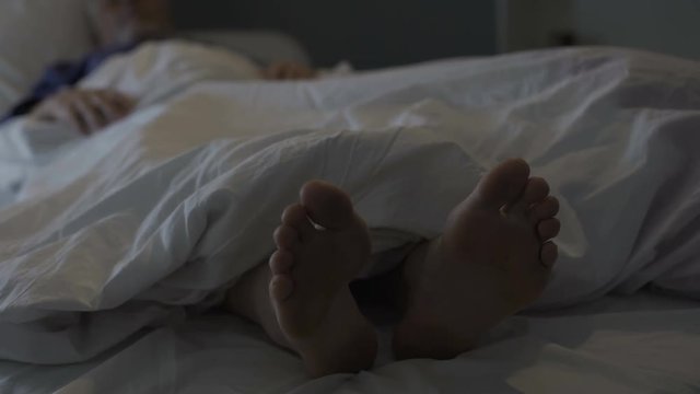 Sleeping man scratching his feet, nasty smell and discomfort due to foot fungus