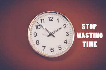 stop wasting time word with wall clock on red background, business concept
