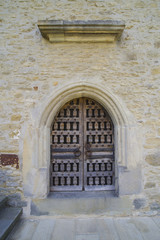 Fototapeta na wymiar Stone wall with barred wooden door