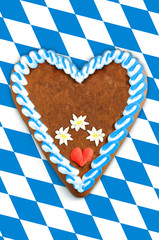 Obraz premium Oktoberfest Gingerbread heart with copy space on bavarian white blue flag.