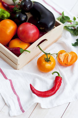 Fresh vegetables, tomatoes, peppers, aubergines, chilli pepper in a wooden box in the open air. Vegetable background.