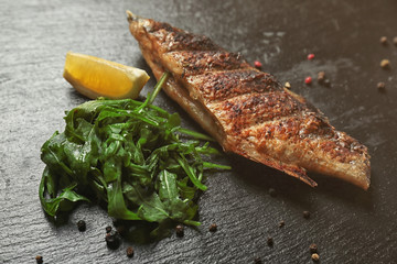 Delicious fish with lemon and arugula on table