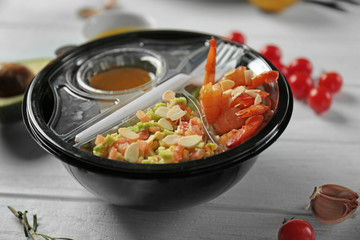 Plastic container with delicious food on wooden table