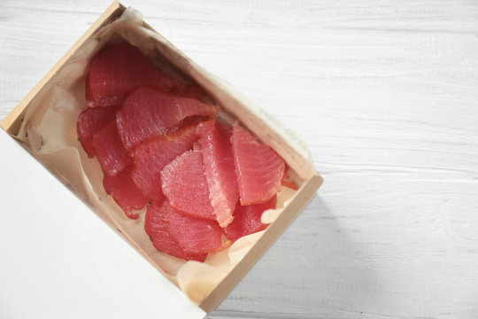 Cardboard box with delicious tuna on wooden table