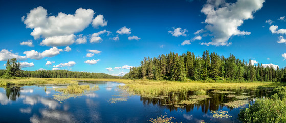 Blue mirror lake reflections of clouds and landscape. Ontario, Canada.
