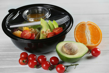 Plastic container with delicious food on wooden table