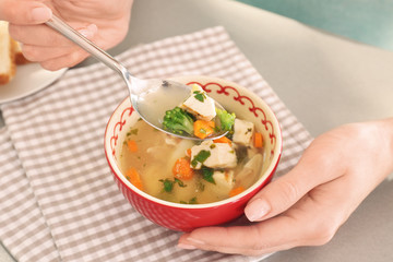 Woman eating homemade chicken soup on table
