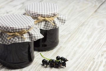  Low sugar black currant jam in  glass jar on old wooden background.  Selective focus, space for text.  