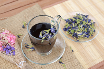 Juice of Butterfly pea in glass on wooden table. Herb drink with Dried Butterfly pea.