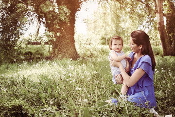 Fototapeta premium Pregnant mother playing with little daughter in park. Mother and daughter in nature.