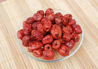 Jujube, Chinese dried red date fruit on a plate against wood background.