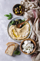 Homemade traditional spread hummus with chopping olives, oil and herbs on blue plate, served with...
