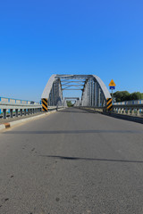 Grey steel bridge across the Narew river in Tykocin, Poland on a sunny day with clear blue sky